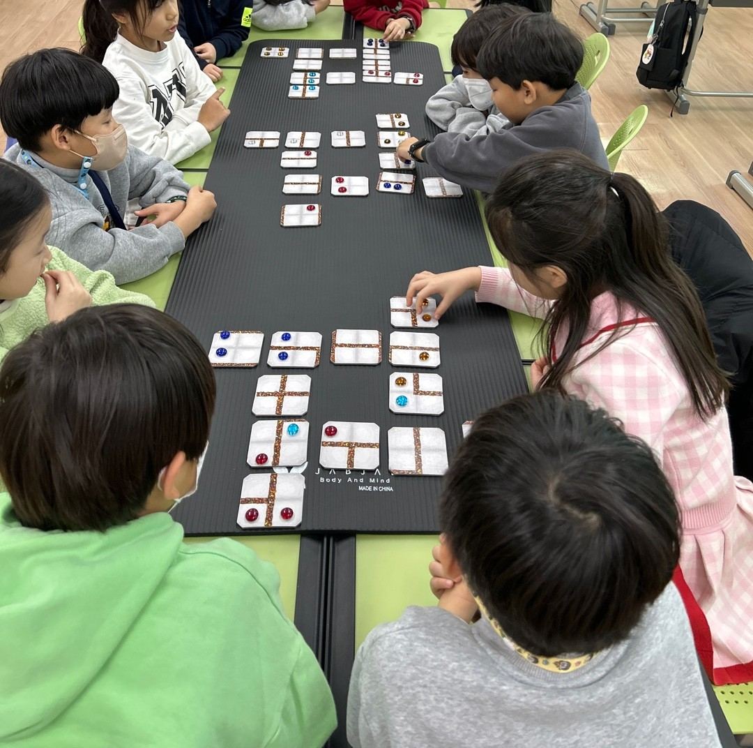책상 위에 카드를 펼쳐 놓고 보드게임 수업을 하는 아이들